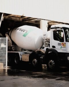 White cement mixer truck at construction site, ready for transportation.